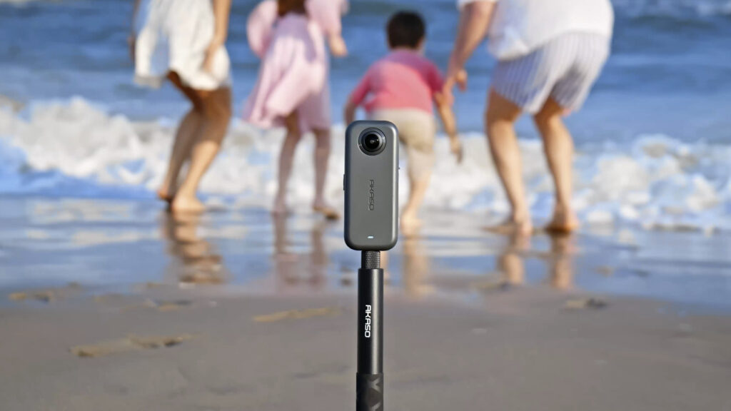 Akaso 360 camera attached to a selfie stick, filming a family on a beach