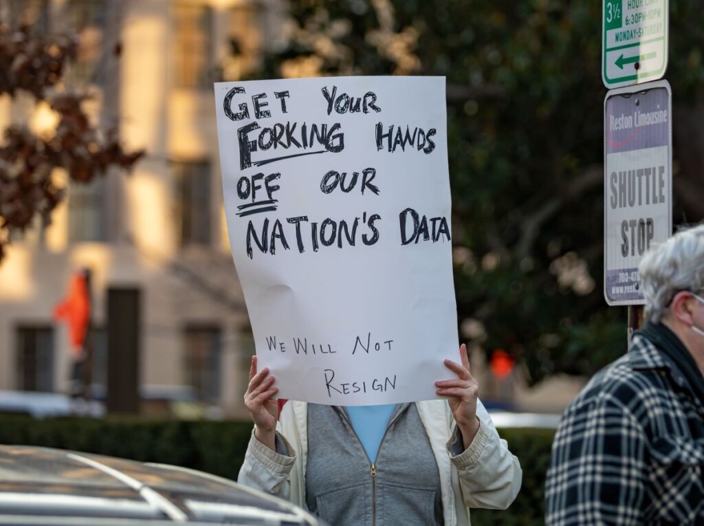 DOGE staffer with access to Americans’ personal data leaked private xAI API key a photo of a protesters in Washington DC with a sign that says "GET YOUR FORKING HANDS OFF OUR NATION'S DATA"