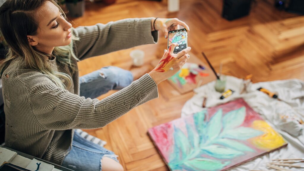 A woman taking a photo of a painting
