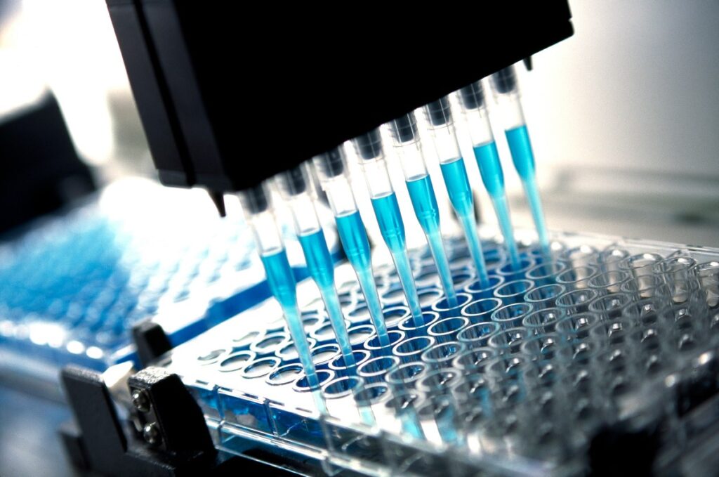 Robotic multichannel pipette device portions out blue fluid for medical and pharmaceutical research and testing.