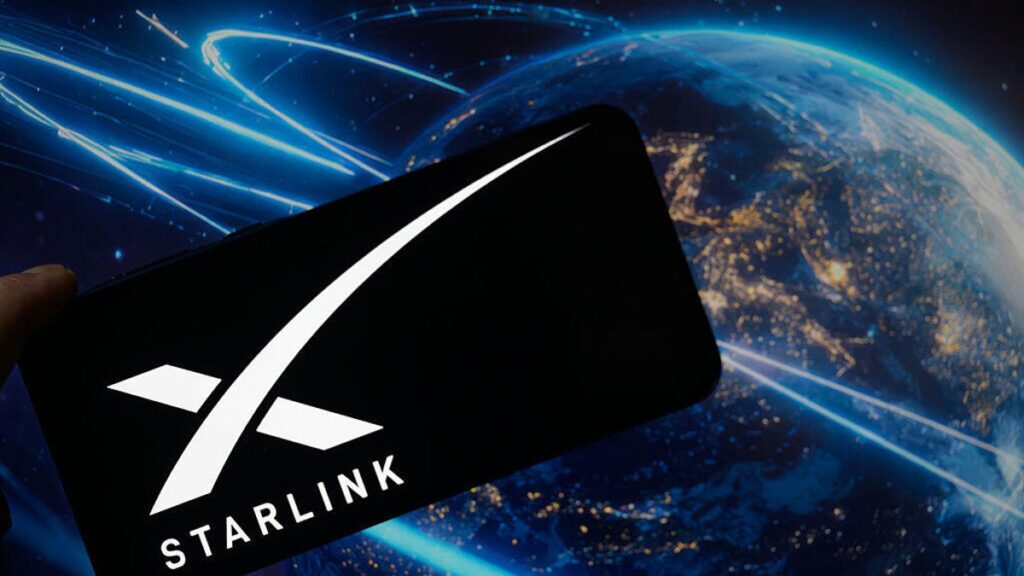 An image of the Starlink logo on a phone, with Earth and satellites in the background (gettyimages-2224910960)