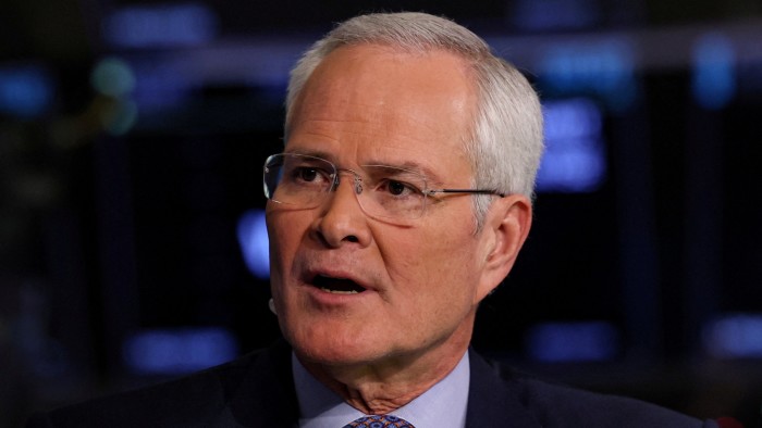 Exxon to ‘pace’ low-carbon spending blaming weak demand and bad policies Darren Woods speaks during an interview, with his mouth slightly open and wearing glasses and a suit.