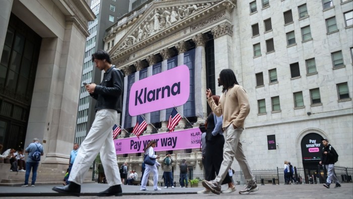 Fintech Klarna records loss as it expands into conventional lending Large pink Klarna banners are displayed on the New York Stock Exchange building as people walk by outside.