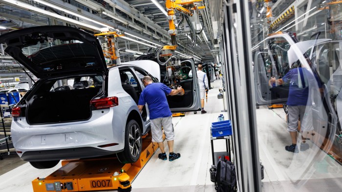 Brussels to give carmakers breathing space on 2030 climate targets Workers assemble Volkswagen ID.3 electric cars on a production line, with open car doors and automated machinery visible.