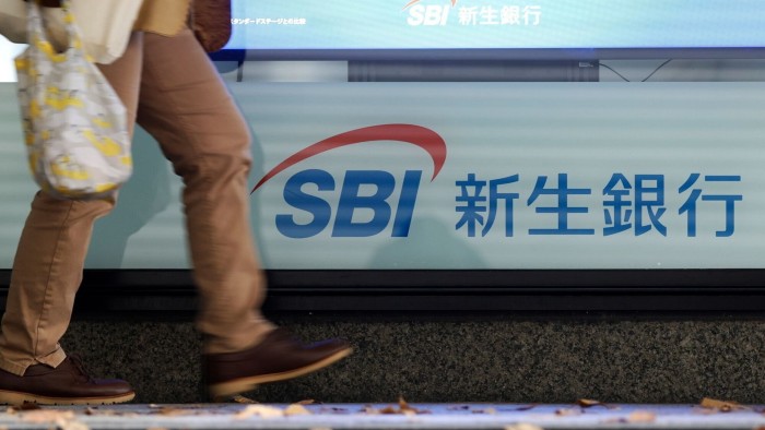 IPO of bubble-era Japan bank seen as trigger for more deals A person walks past signage for SBI Shinsei Bank in Tokyo, with the bank's logo and name in Japanese visible.