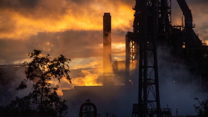 UK watchdog seeks to ‘clean up’ conflicts of interest in ESG ratings Late evening sunlight glows through steam rising from the Tata Steelworks in Port Talbot, silhouetting industrial structures.
