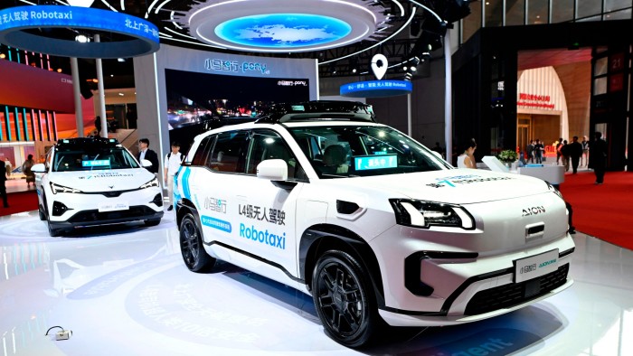 Why China’s robotaxi industry is stuck in the slow lane A Pony.ai AION robotaxi is displayed on a showroom floor, featuring signage for autonomous driving at the Shanghai auto show.